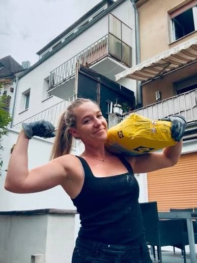 Sabrina Küppers lächelt und hält einen gelben Werkzeugsack über der Schulter